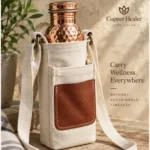 Cream copper water bottle sling bag with shoulder strap and brown front pocket, shown holding a hammered copper bottle.