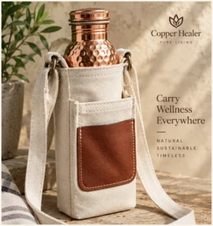 Cream copper water bottle sling bag with shoulder strap and brown front pocket, shown holding a hammered copper bottle.